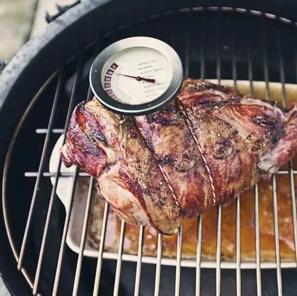 checking temperature of BBQ leg of lamb