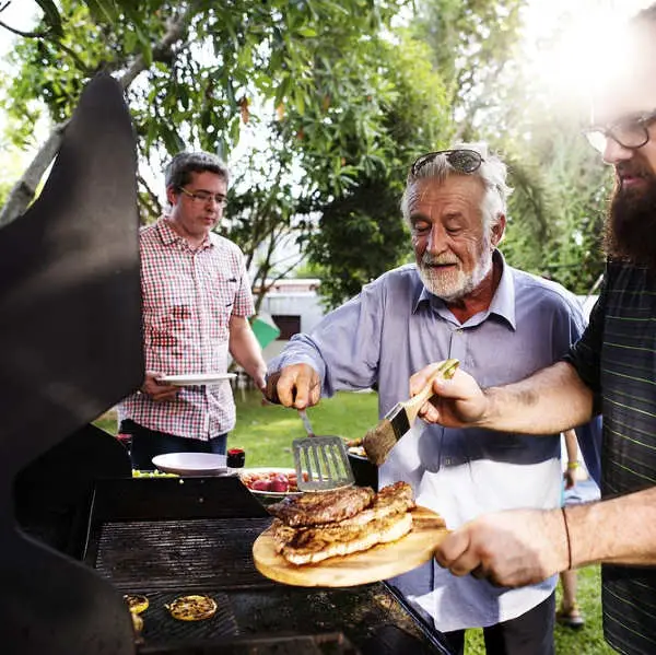 man helping cooking steaks on gas grill